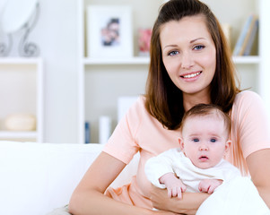 Fototapeta na wymiar Portrait of happy young mother with newborn baby at home