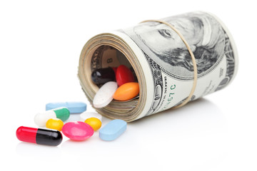 Money rolled up with pills flowing out isolated on white