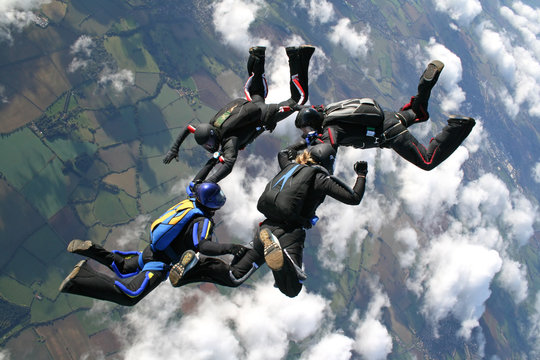 Four skydivers in freefall on a sunny day
