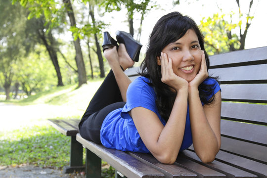 An Asian woman lying on a bench