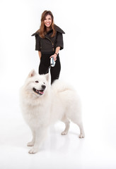 young woman walking a white dog in front of her