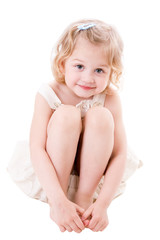 Obraz premium Smiley little girl wearing a linen sundress sitting on white bac