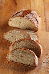 Sliced loaf of fresh bread on wooden desk
