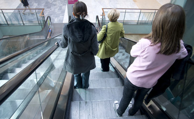 trois personnes dans un escalator de centre commercial