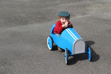 Junge in seinenem blauen Tretauto