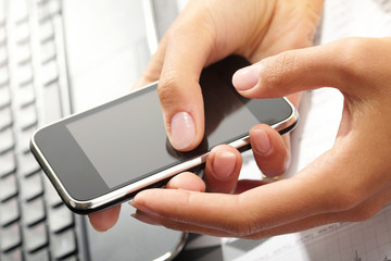 Using a PDA mobile phone with laptop keyboard background,