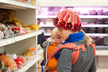 Young mother with toddler girl shopping in supermarket