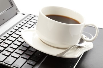 Cup of fragrant coffee on a laptop