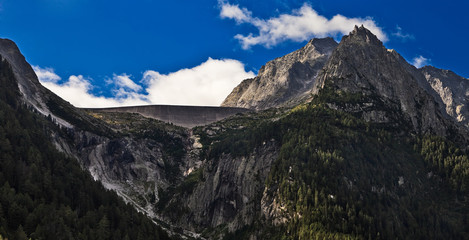 Alpine landscape view with artificial reservoir concrete dam.