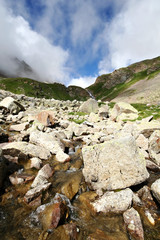 Flowing glacier stream among stones. Caucasus mountains..