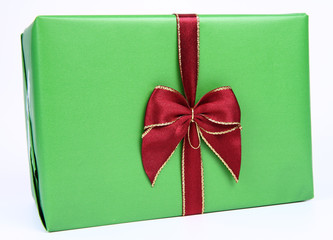 Gift in green wrapping with a red bow on white background