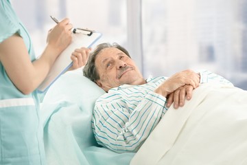 Obraz na płótnie Canvas Nurse taking notes of old patient