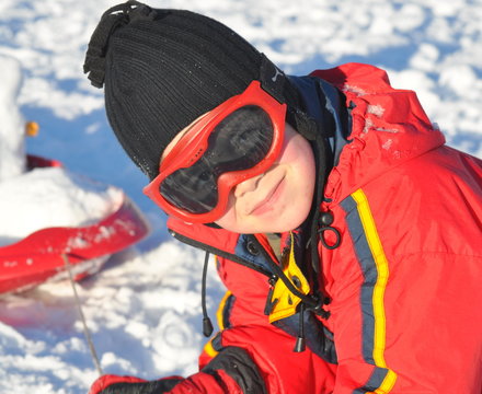 sport d'hiver enfant gar&ccedil;on joyeux couch&eacute; dans la neige