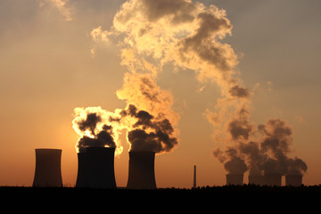 chimney and cooling towers of power plant during sunset