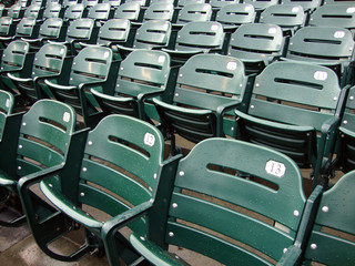 Rows of empty wet green stadium seats, seats number 13, 12, 11