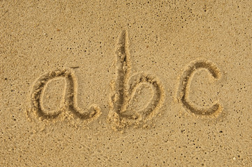 alphabet letters a b c handwritten in sand on beach