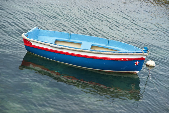 Small, blue rowboat moored in a marina