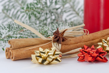 Zimtstangen mit winterlicher Dekoration auf weissem Hintergrund