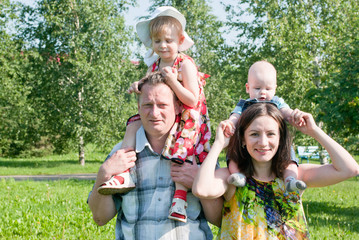 Fototapeta premium children sit on the necks of the parents, happy family
