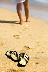 Beach slippers on sand and female feet