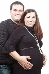 Happy pregnant wife with husband hugging her belly