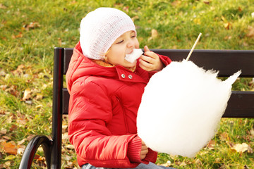 Little girl eats sweets in the park - obrazy, fototapety, plakaty