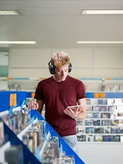 Aluminium Prints Music store guy listening music in cd store