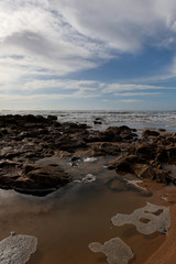 Fototapeta na wymiar plage,rochers, soleil et nuages