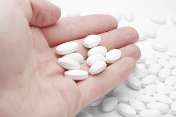 Pills in male palm over white table