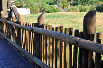 Fence made from wooden logs with a field as background