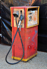 An old retro red gas pump with a black hose