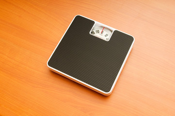 Dieting concept with scales on the wooden floor