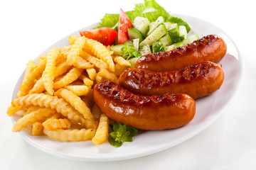 Grilled sausages, French fries and vegetables