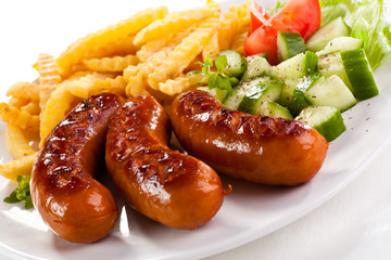 Grilled sausages, French fries and vegetables