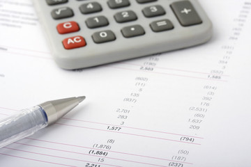 Business financial reports with pen and calculator
