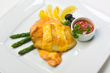 Fish with mayonnaise, served with asparagus, olives, lemon and k