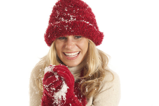 Portrait of young woman with red hat and gloves making snowball