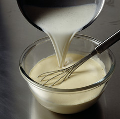 Verser le lait bouillant sur le mélange jaunes d'oeufs-sucre en fouettant 