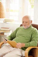 Older man relaxing at home, reading book