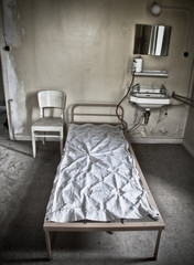 A bed sitting in a room of an abandoned hospital