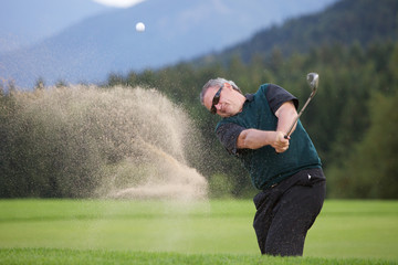 Professioneller Golfer chippt den Ball aus dem Sandbunker