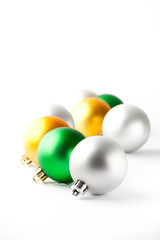 Green, gold and silver Christmas baubles on white