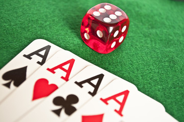 Four aces and red dice on green background