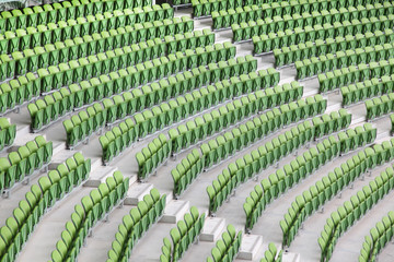 Naklejka premium Rows of folded, green, plastic seats in empty stadium.