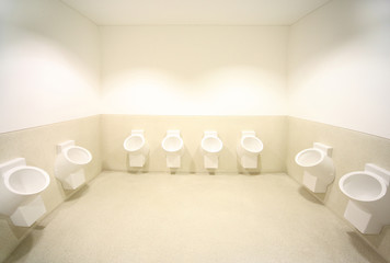 several white urinals. big bright clean toilet.