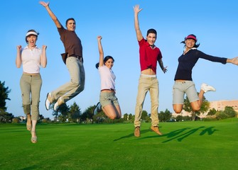 group of young people jumping outdoors grass