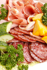 Meat and sausages with parsley and vegetables on white plate