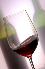 glass of red wine with bottles in the background