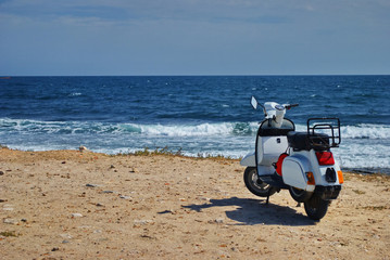 White motor scooter with sea in background