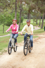 Senior couple riding bicycle in park